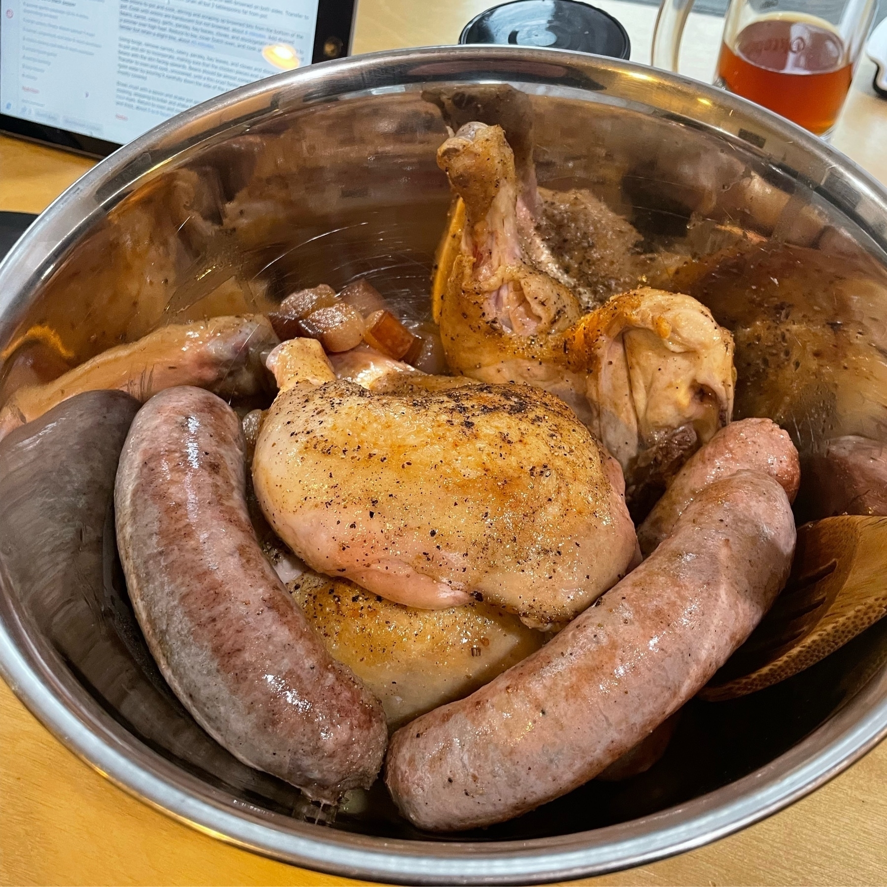 lightly browned sausage and chicken in a metal bowl
